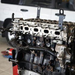 Detailed view of a car engine in an auto repair shop with a blurred vehicle in the background.